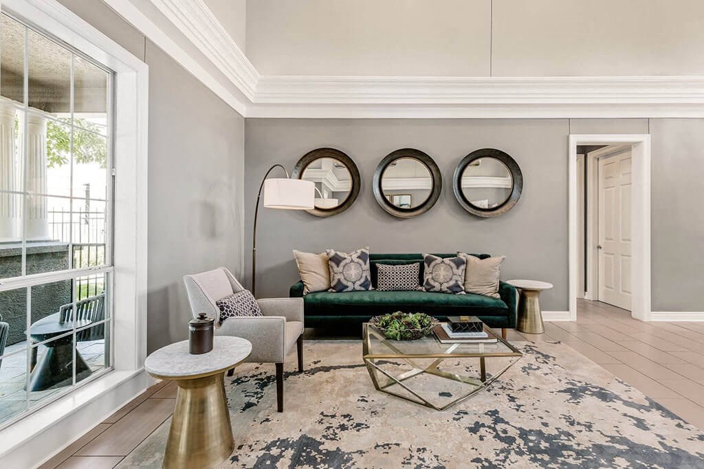 a living room with a green couch and two mirrors