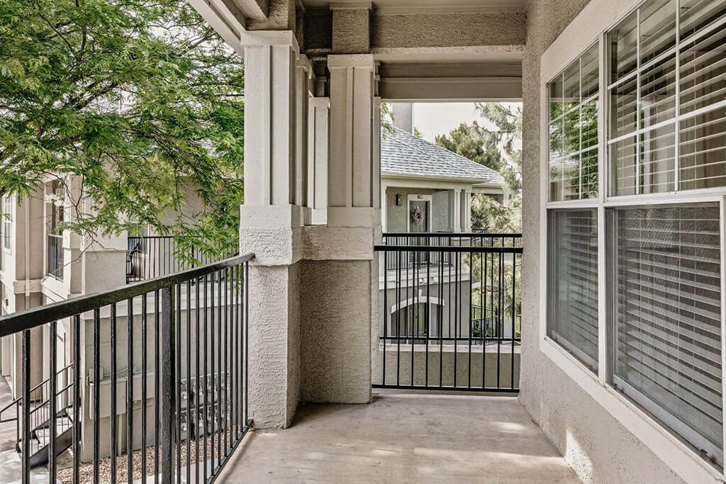 a balcony with a fence and a house in the background