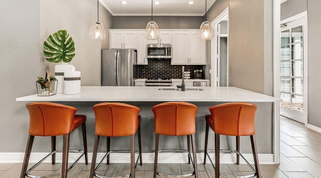 a kitchen with a counter and four orange chairs