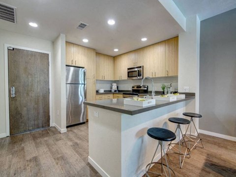 a kitchen with a bar and a stainless steel refrigerator