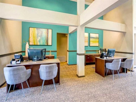a hotel lobby with two desks and chairs and computers
