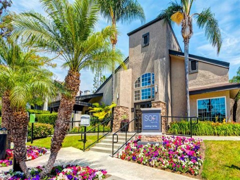 a building with palm trees and flowers in front of it