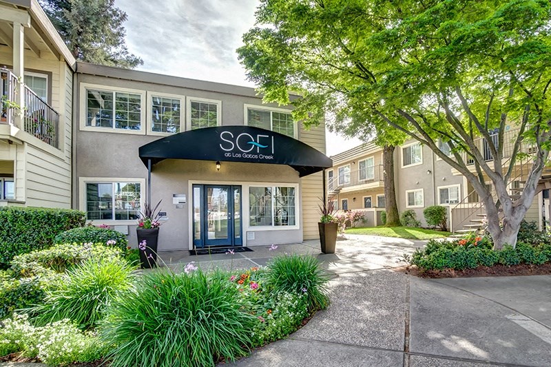 the entrance to a building with a sidewalk and trees in front of it