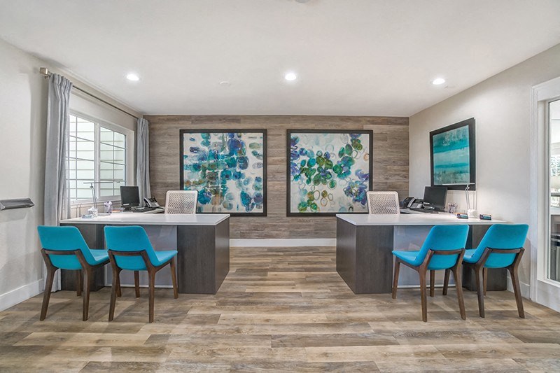 an office with blue chairs and a desk with a computer