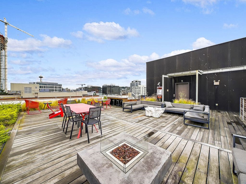 a rooftop patio with tables and chairs and a city in the background