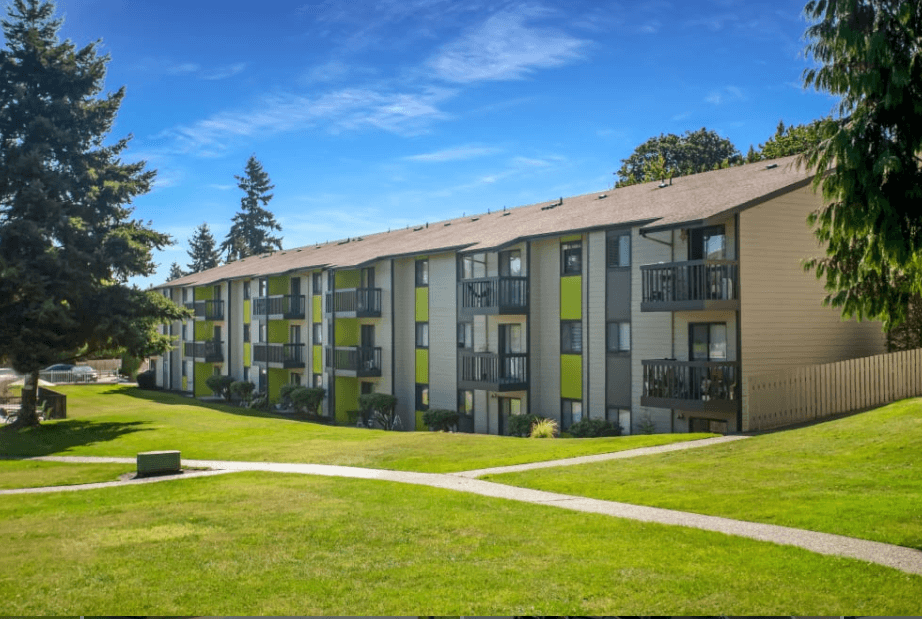 an exterior view of an apartment building with green grass and trees