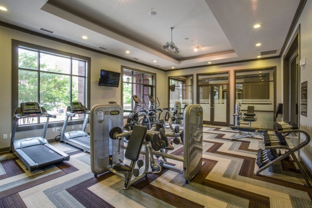 the gym has a wall of windows and cardio equipment