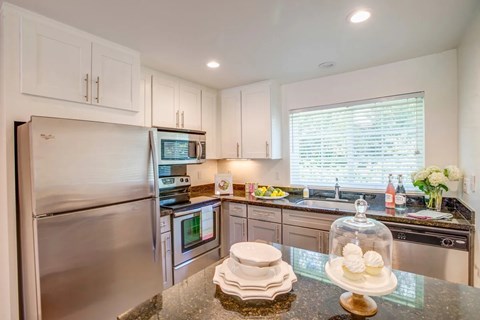 A modern kitchen with a stainless steel refrigerator and a glass dome on the island.