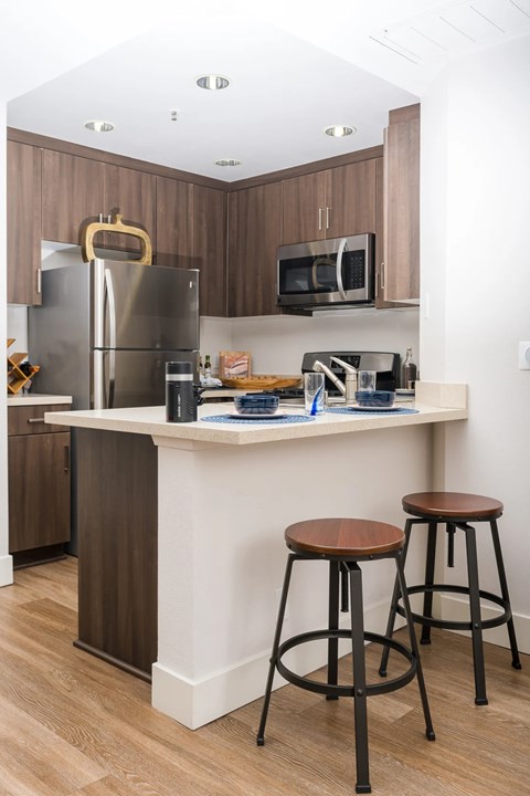 A kitchen with a white counter and brown stools.
