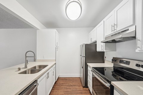 an empty kitchen with white cabinets and stainless steel appliances