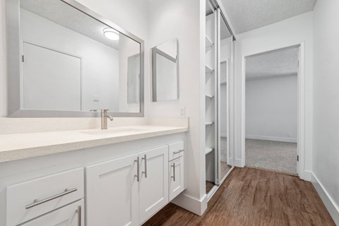 a bathroom with white cabinets and a mirror and a shower