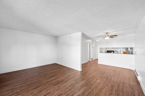 the living room and dining room of an apartment with white walls and wood floors