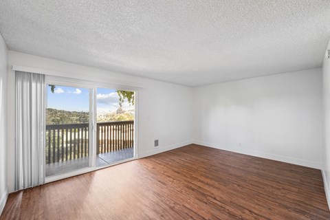 an empty living room with wood flooring and a balcony