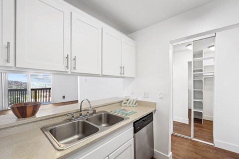 a kitchen with white cabinets and a stainless steel sink