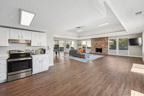 the living room and kitchen of a new home with white cabinets and a fireplace