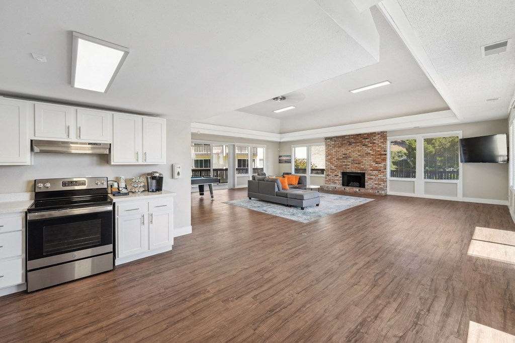 the living room and kitchen of a new home with white cabinets and a fireplace