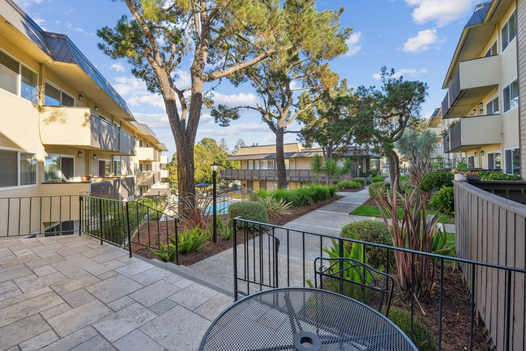 a patio with a table and chairs in front of an apartment building
