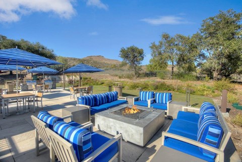 A patio with blue and white striped cushions and a fire pit.