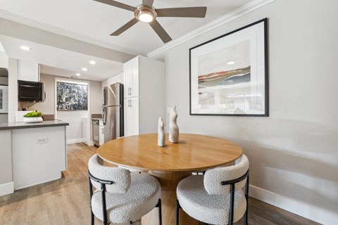 A modern dining room with a round wooden table and grey chairs.