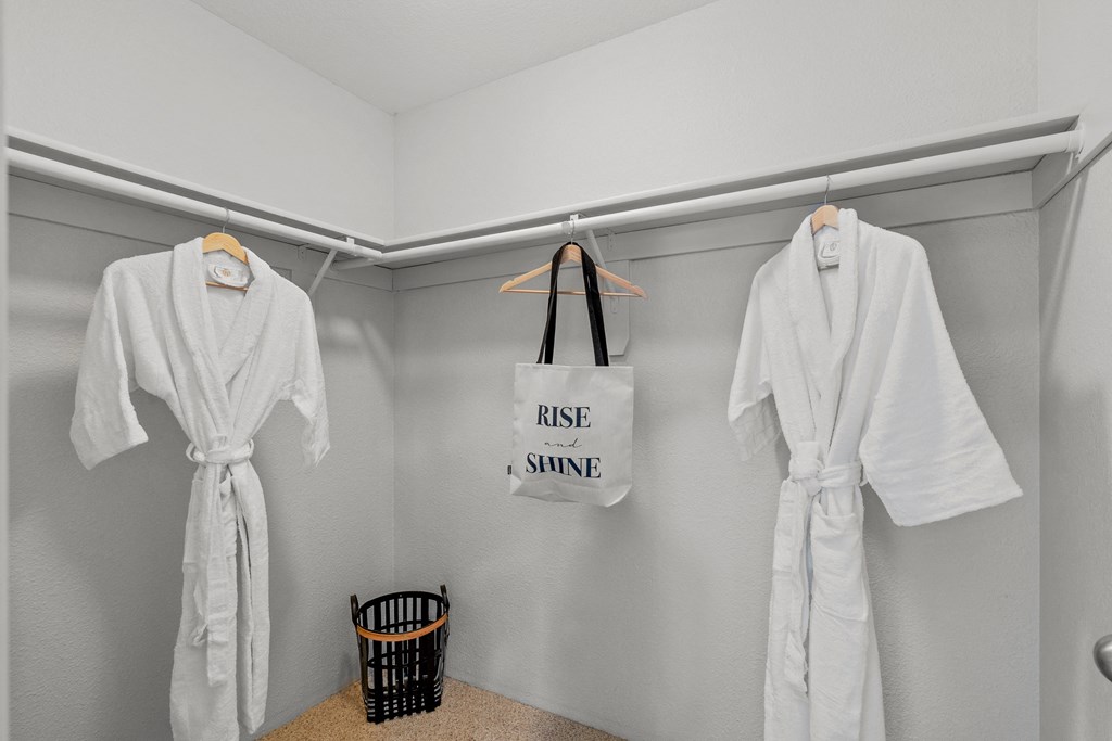 a room with two white robes and a tote bag