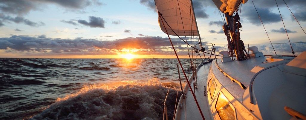 the sun setting over the ocean from a sail boat