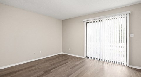 an empty living room with a large window and wood flooring