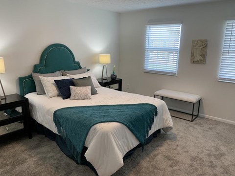 a bedroom with a bed and a chair and a window