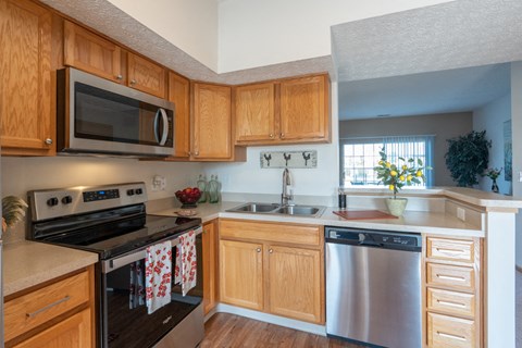 A kitchen with wooden cabinets and a stainless steel dishwasher.