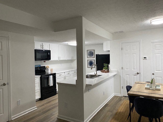 A kitchen with a black fridge and a black microwave.
