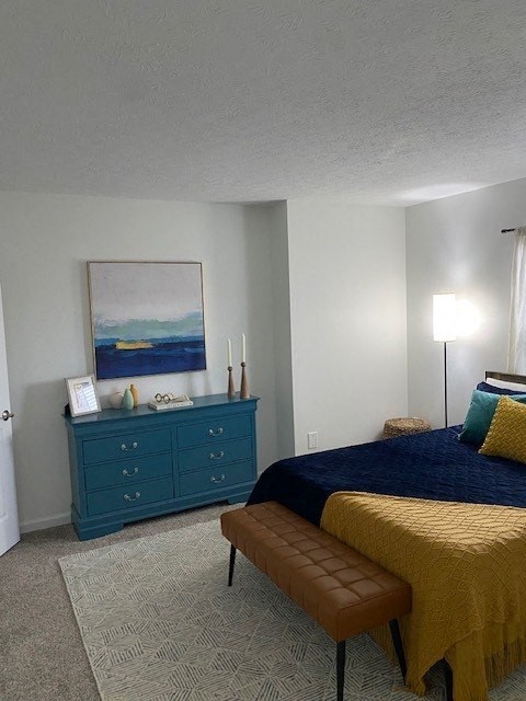 A bedroom with a bed, dresser, and a painting on the wall.