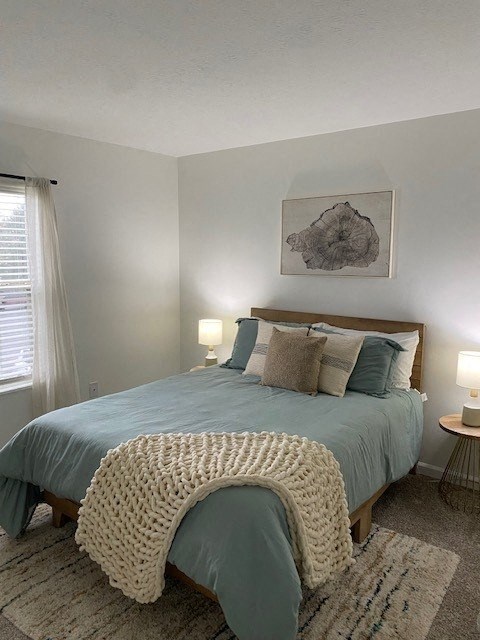 A bedroom with a bed covered in a blue comforter and a white knitted throw.