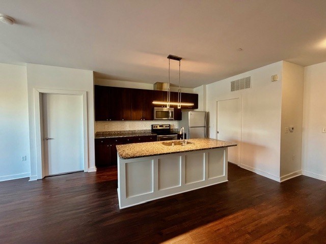 A kitchen with a granite countertop and a hanging light fixture.