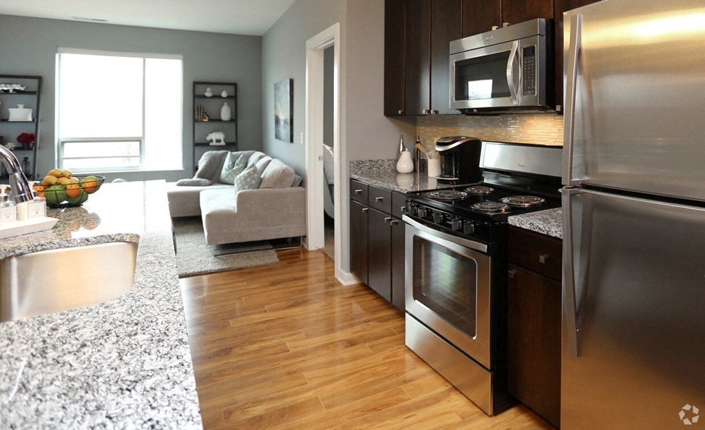 a kitchen and living room with stainless steel appliances and granite counter tops