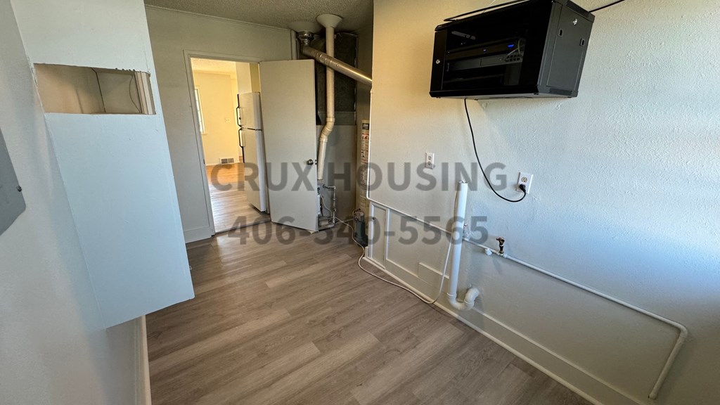 A room with a television on the wall and a doorway leading to another room.