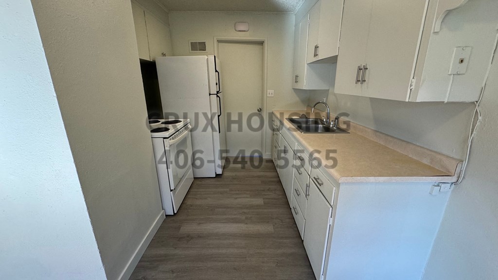 A kitchen with white cabinets and a wooden countertop.