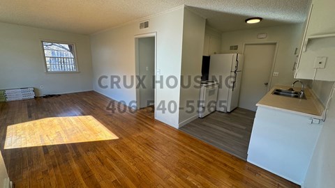 A room with wooden floors and white walls, with a window on the left side.