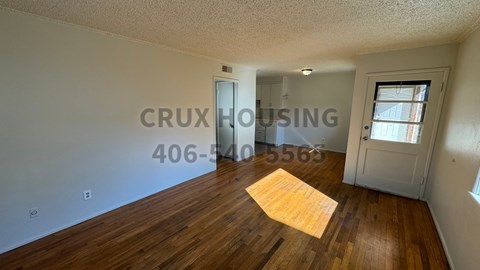 A room with wooden floors and a door leading to another room.