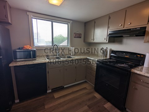 A kitchen with wooden floors and a stove top oven.