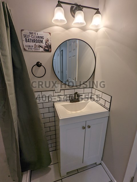A bathroom with a mirror, sink, and a sign that says "This is a self-cleaning bathroom. Clean up when done.".