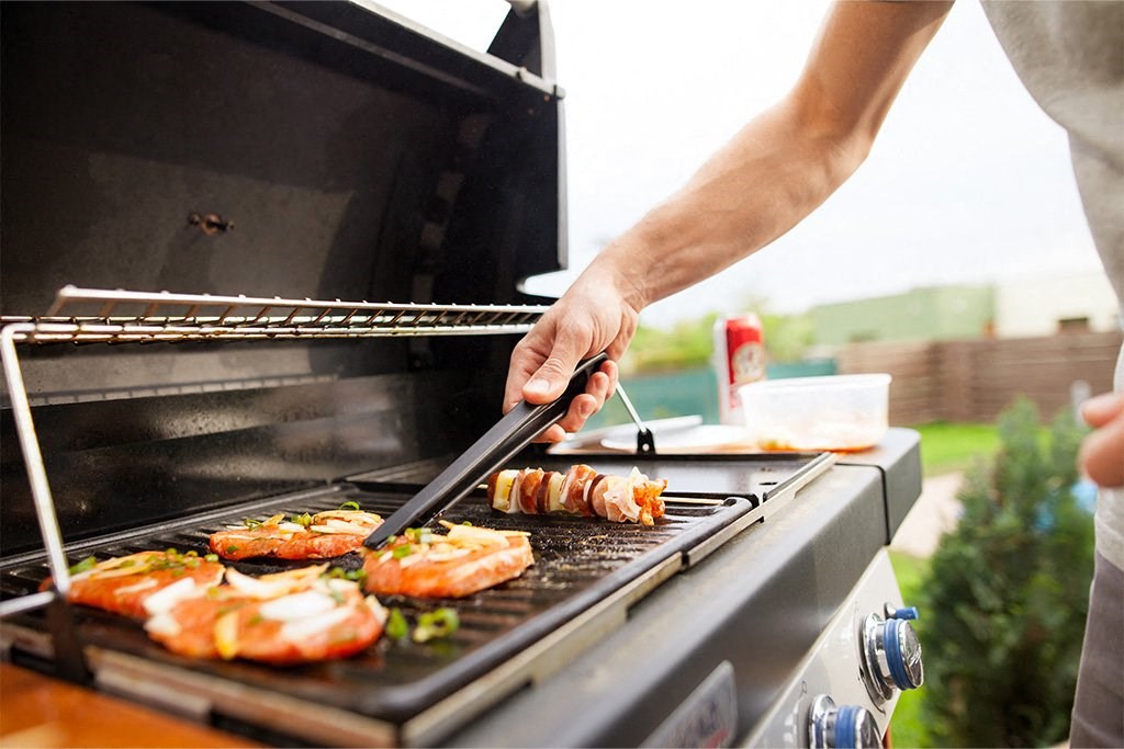 a man grilling food on a grill at Morea Apartments, Pompano Beach, FL