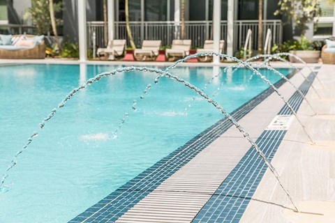a swimming pool with sprinklers in front of a building
