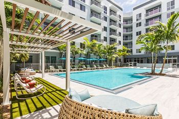 A pool area with a white pergola and a blue pool at Morea Apartments, Pompano Beach, 33062