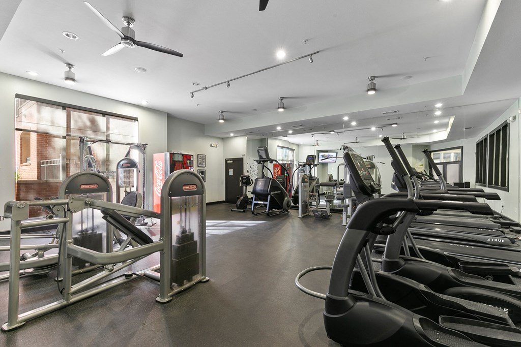 a gym with treadmills and other exercise equipment in a building with windows