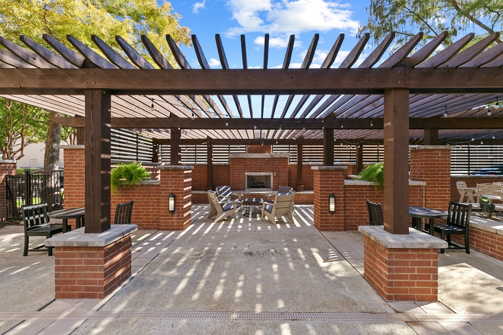 a patio with a pergola and a brick fireplace
