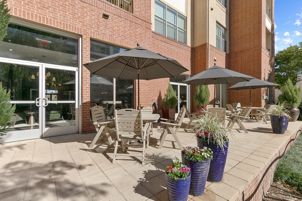 a patio with tables and umbrellas outside of a building