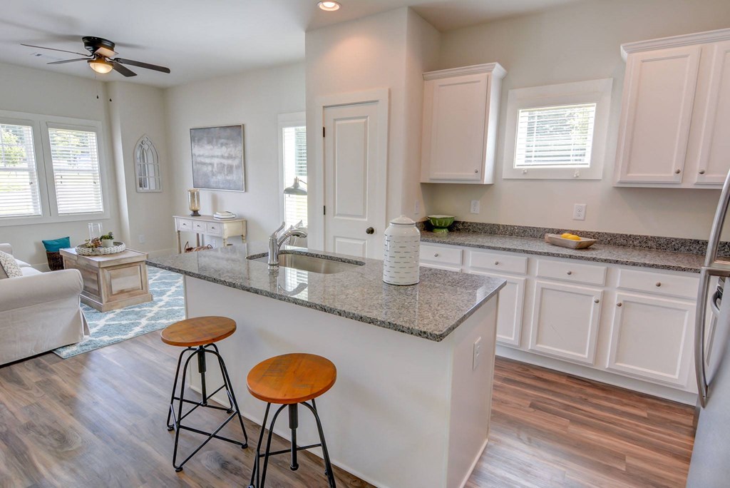 a kitchen and living room with white cabinets and a granite counter top