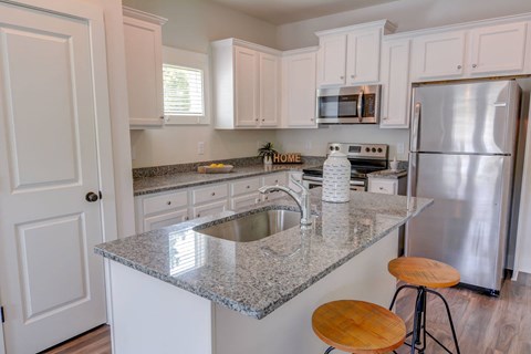 a kitchen with a granite counter top and a stainless steel refrigerator