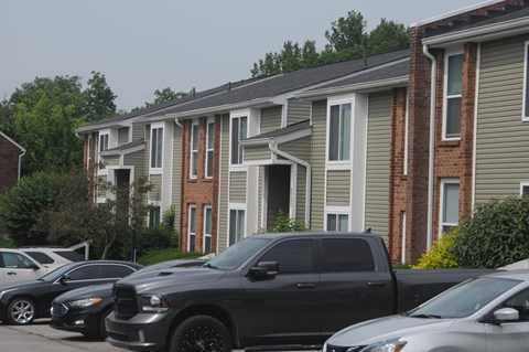 A black SUV is parked in front of a row of houses.