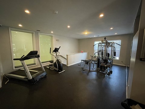 A spacious gym with a treadmill, exercise bike, and weightlifting equipment.