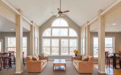 A living room with a large window and a ceiling fan.
